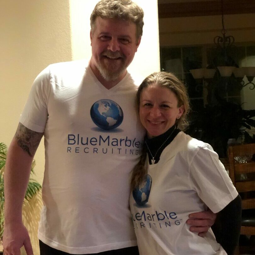 A man and woman wearing white shirts with blue logo.